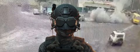 Un soldat avec un masque pour drone FPV tet derrière lui de la fumée