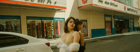 Deux filles en robes vintage dos à dos devant un cinéma à l'ancienne