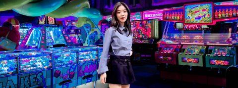 Une jeune asiatique avec une tenue d'écolière modernisée dans une salle de jeux d'arcade