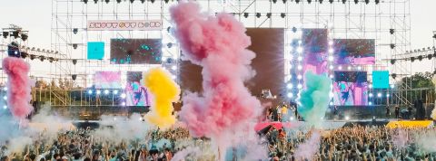Un concert en pmein air, avec fumigènes de couleurs et une foule de spectateurs