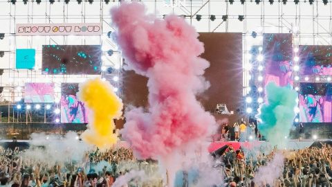 Un concert en pmein air, avec fumigènes de couleurs et une foule de spectateurs
