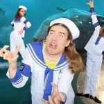 Un jeune toktokeur avec un costume de marin désuet sur une image de sous-marin torpille
