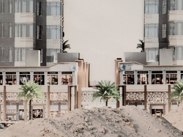 Deux immeubles modernes au Koweit derière des monceaux de sable et des palmiers