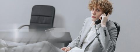 Un jeune homme les pieds sur son bureau dans un univers gris