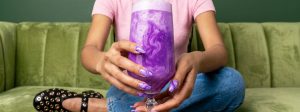 Une fille sur un canapé vert matcha tient un latte Ube de couleur violette